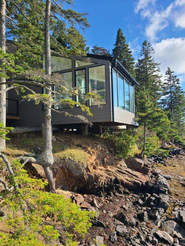 Modern home along the rocky Maine coastline with floor-to-ceiling windows