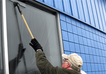 Sun Services technician cleaning exterior windows on a residential property in Maine